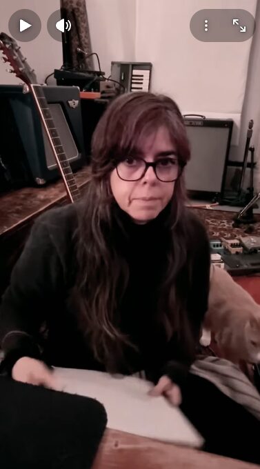 Clara slightly smiling with a paper notebook and the cat to the right.